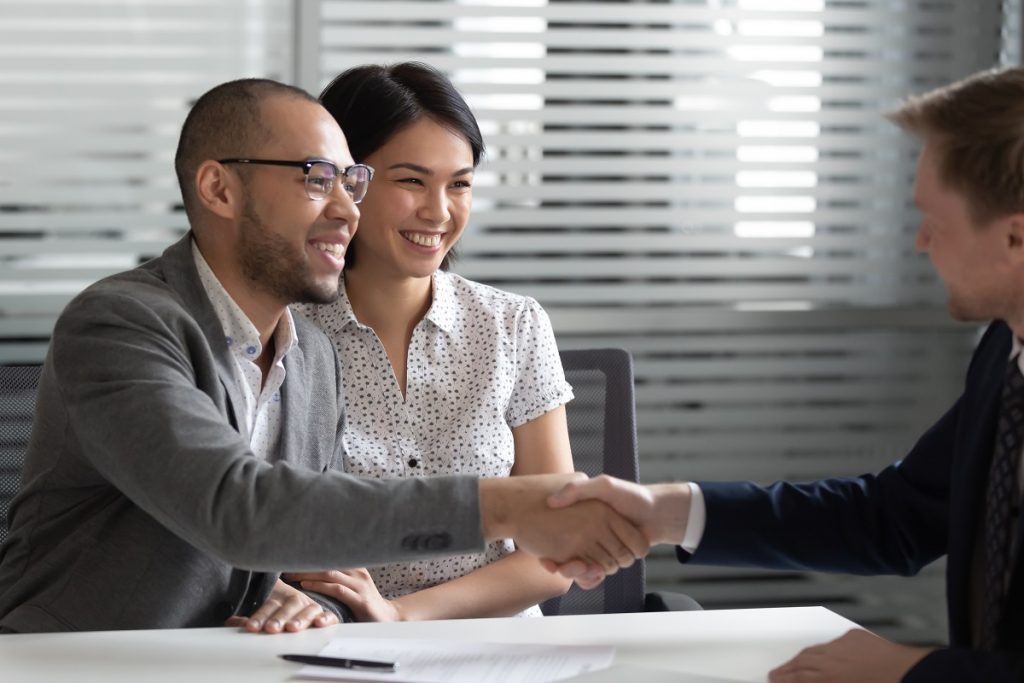 Cheerful married spouse shaking hands with financial advisor